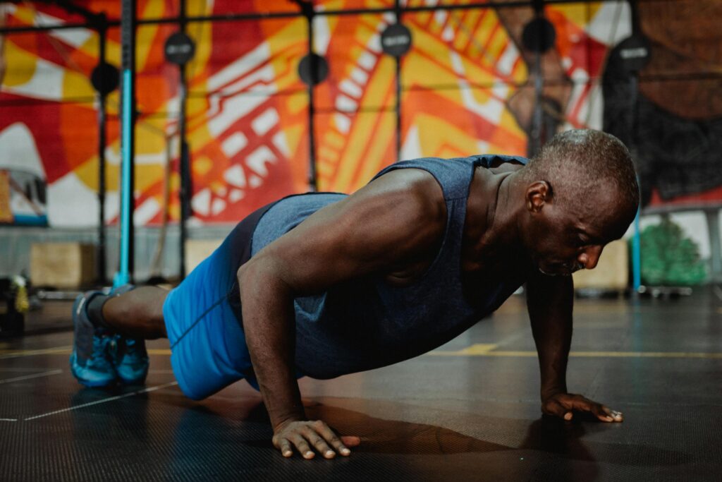 Adult man doing push-ups in a colorful gym setting, promoting fitness and health.
